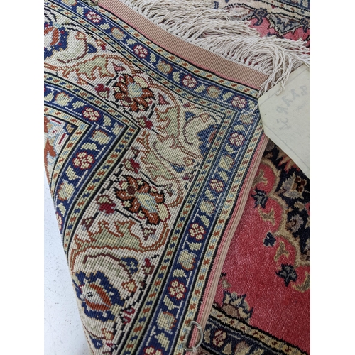 165 - A Kayson silk prayer rug, floral decoration on a red ground, multiguard borders and tasselled ends 1... 