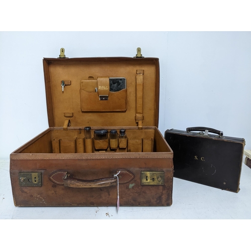 166 - A vintage leather travelling case with four silver topped glass bottles, London 1911, and other item... 