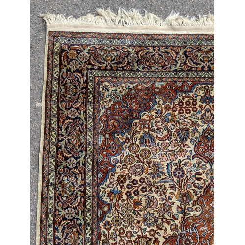 226 - A pure silk Persian Kashan rug with a central emblem decorated with a symmetrical abstract design wi... 