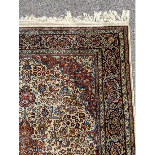 226 - A pure silk Persian Kashan rug with a central emblem decorated with a symmetrical abstract design wi... 