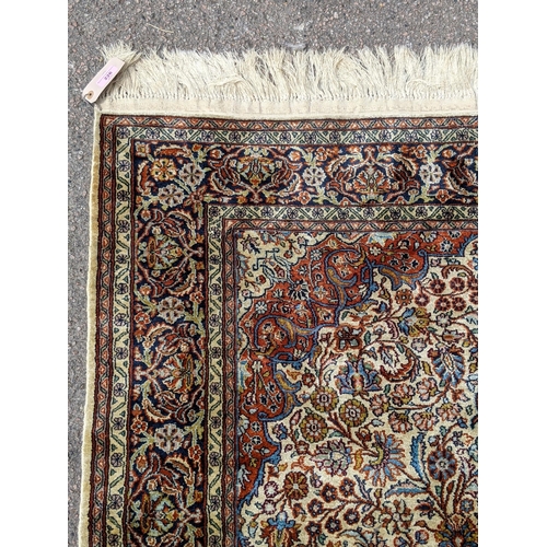 226 - A pure silk Persian Kashan rug with a central emblem decorated with a symmetrical abstract design wi... 