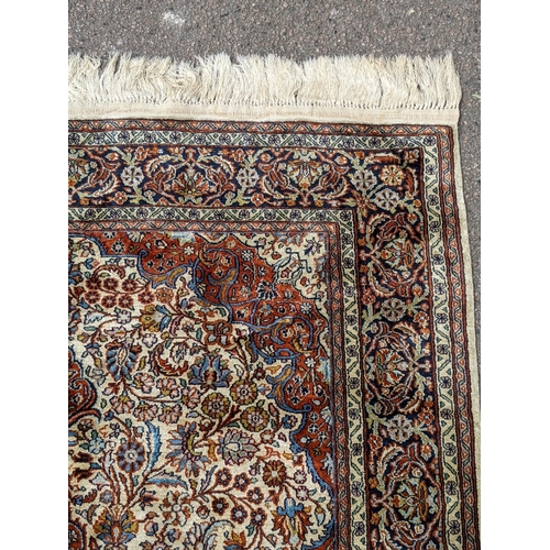 226 - A pure silk Persian Kashan rug with a central emblem decorated with a symmetrical abstract design wi... 