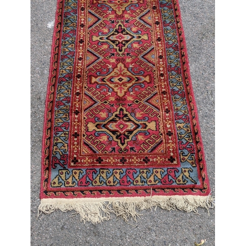 228 - A wool Eastern Turkestan Kashquai runner with eleven repeated central medallions five of one design ... 