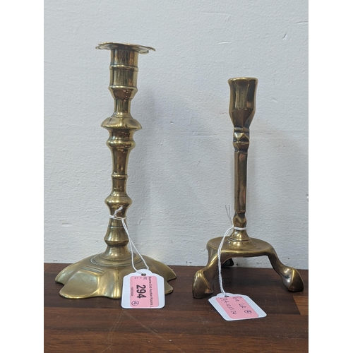 294 - Four brass candlesticks to include a pari decorated in an Art Nouveau style and an Arts and Crafts s... 