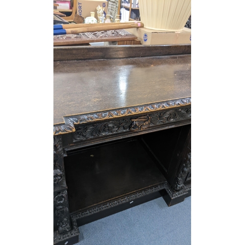 336 - A late 19th century Edwards & Roberts heavily carved oak sideboard having three drawers above an ope... 