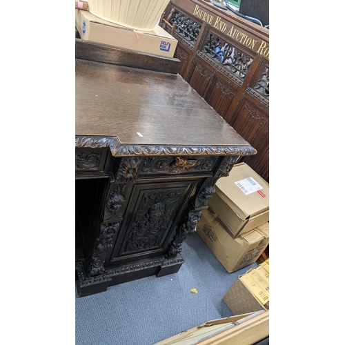 336 - A late 19th century Edwards & Roberts heavily carved oak sideboard having three drawers above an ope... 