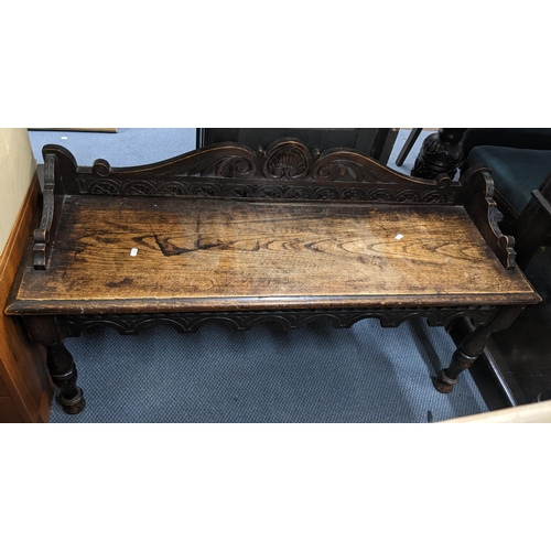 341 - A late 19th century oak carved window seat having a raised back, shaped apron and turned legs, 66cm ... 