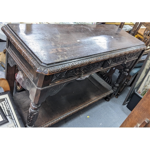 345 - A late 19th century heavily carved oak two tier side table inset with two drawers, acanthus leaf car... 