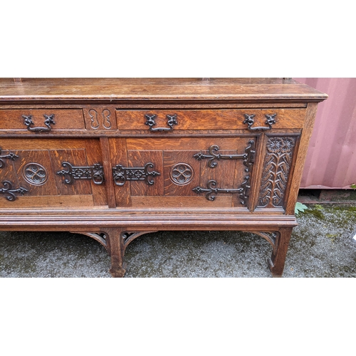 566 - An early 20th century Hampton & Sons Gothic revival oak dresser, the top having a moulded stepped co... 