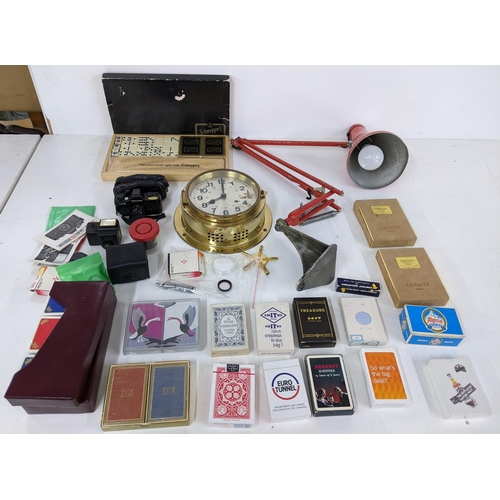 557 - A mixed lot to include a collection of playing cards, a brass German wall clock, an industrial angle... 