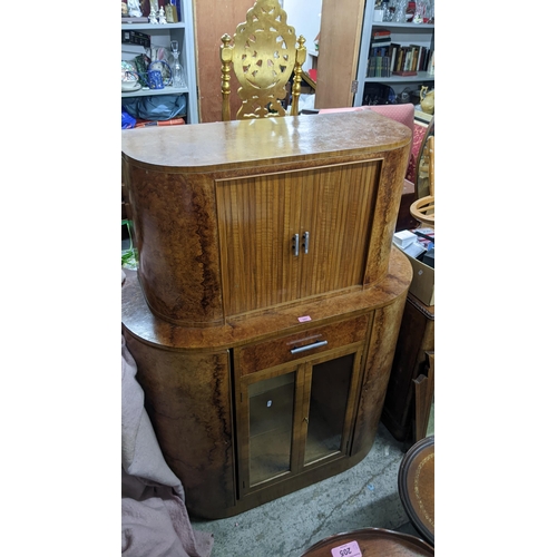 597 - An Art Deco walnut drinks/cocktail cabinet with tambour doors, enclosing a mirrored back, above a dr... 