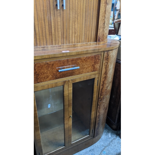 597 - An Art Deco walnut drinks/cocktail cabinet with tambour doors, enclosing a mirrored back, above a dr... 