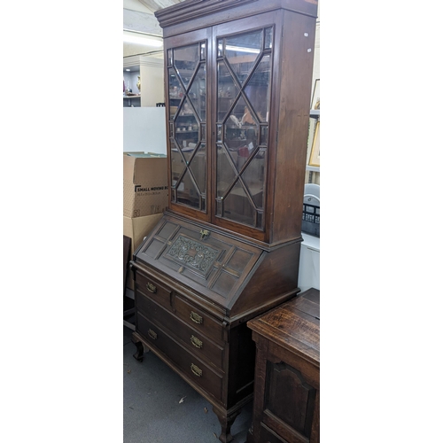 609 - A Victorian mahogany bookcase cabinet with twin glazed doors over a carved fall front two short and ... 