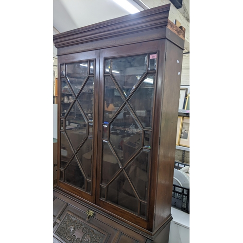 609 - A Victorian mahogany bookcase cabinet with twin glazed doors over a carved fall front two short and ... 