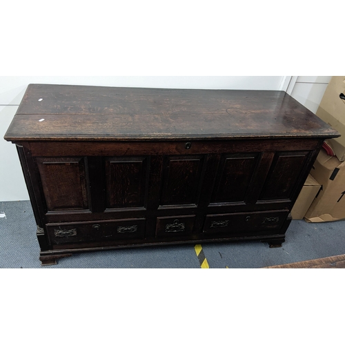 610 - A George III oak chest with a hinged top over a panelled front and three drawers on ogee bracket fee... 