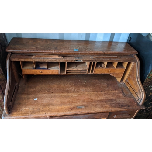 279 - An early/mid 20th century oak roll top tambour desk, opening to reveal fitted drawers and pigeon hol... 