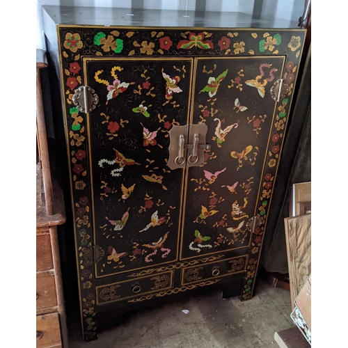 290 - An oriental black lacquered two door cabinet, decorated all over with flowers and butterflies, two d... 