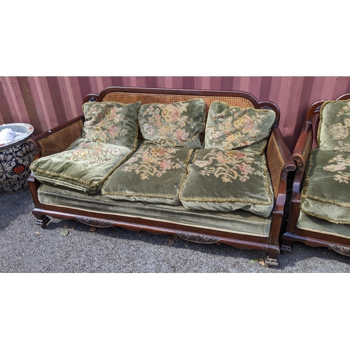 327 - An early 20th century Bergere three piece suite, the mahogany frames having scrolled arms, cloud sha... 