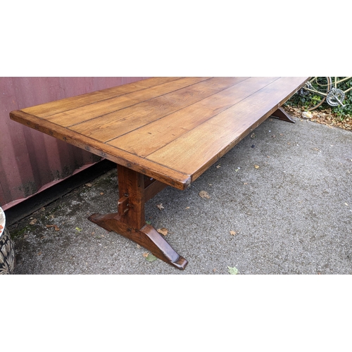 329 - A large 19th century French farmhouse oak dining table, having two trestle ends united by a single s... 