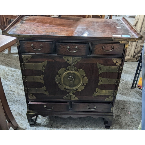 262 - A 20th Century Korean side Cabinet, twin cupboard doors with brass strapwork and other decorations w... 