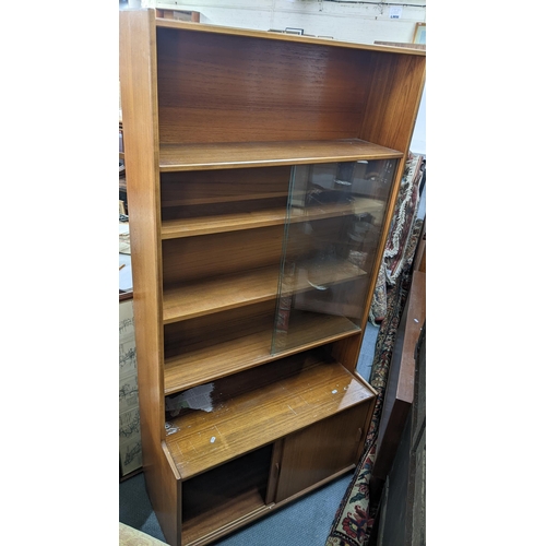 503 - A mid 20th century 'Gibbs Furniture' teak bookcase having glazed doors, open shelves and cupboard do... 