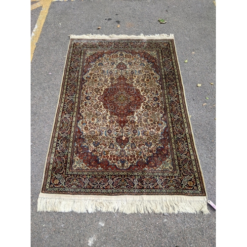 520 - A pure silk Persian Kashan rug with a central emblem decorated with a symmetrical abstract design wi... 