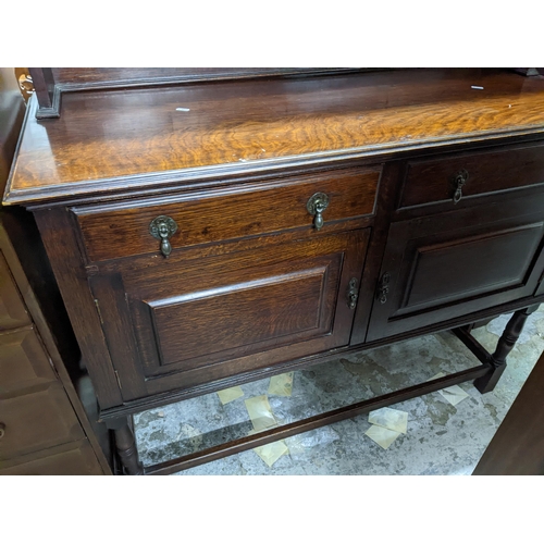 558 - An early to mid 20th century oak dresser, three open plate shelves above a base of two short drawers... 