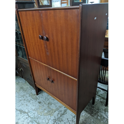 559 - A Younger Ltd mid 20th century teak drinks cabinet, twin doors revealing a fitted interior of glass ... 