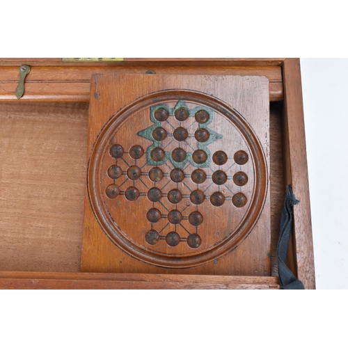 110 - An Edwardian mahogany games compendium, containing a solitaire board with marbles, draught pieces, c... 