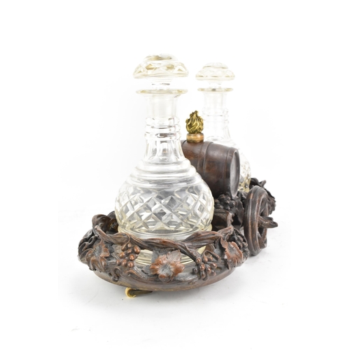 154 - A late 19th century black forest oak carved wine decanter wagon, the centre with a barrel inset with... 