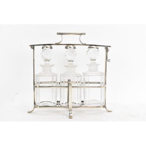 171 - An Art Deco French silver plated liquor tantalus, having three decanters, the frame having a hinged ... 