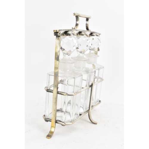 171 - An Art Deco French silver plated liquor tantalus, having three decanters, the frame having a hinged ... 