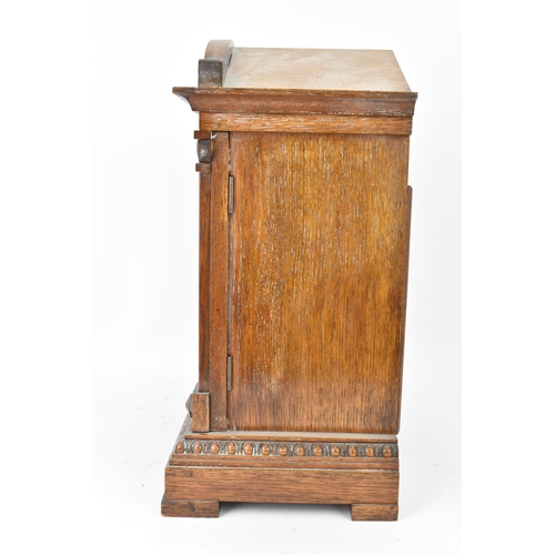 47 - A circa 1900 oak cased mantle clock, the case of architectural form with an arched top, dental mould... 