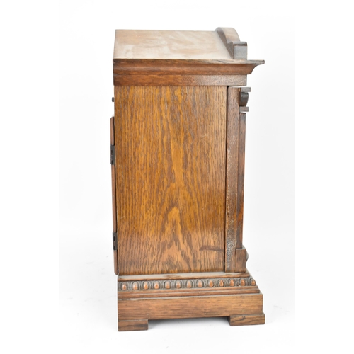 47 - A circa 1900 oak cased mantle clock, the case of architectural form with an arched top, dental mould... 