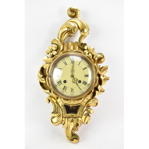 63 - A mid 20th century Louis XVI style giltwood striking cartel wall clock, the ornate case of floral sc... 