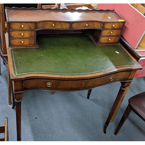 326 - A reproduction mahogany writing desk having a serpentine front, fitted drawers and green leather bai... 