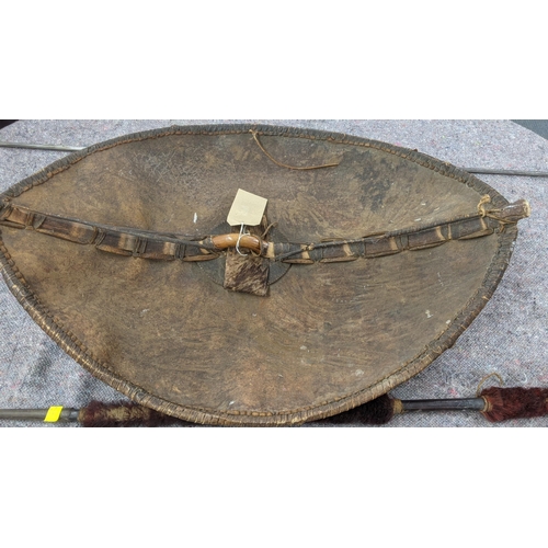 349 - A vintage Masai painted leather shield with a wooden handle, and two African spears, one part wooden... 