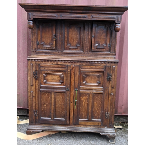 430 - An early 20th century Jacobean style oak court cupboard having a moulded cornice, panelled doors, wr... 