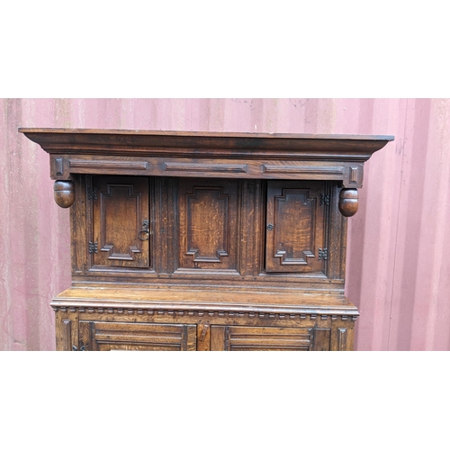 430 - An early 20th century Jacobean style oak court cupboard having a moulded cornice, panelled doors, wr... 