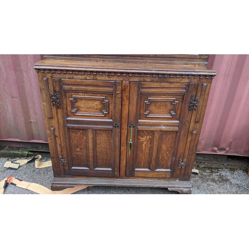 430 - An early 20th century Jacobean style oak court cupboard having a moulded cornice, panelled doors, wr... 