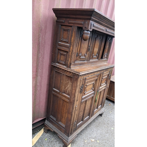 430 - An early 20th century Jacobean style oak court cupboard having a moulded cornice, panelled doors, wr... 