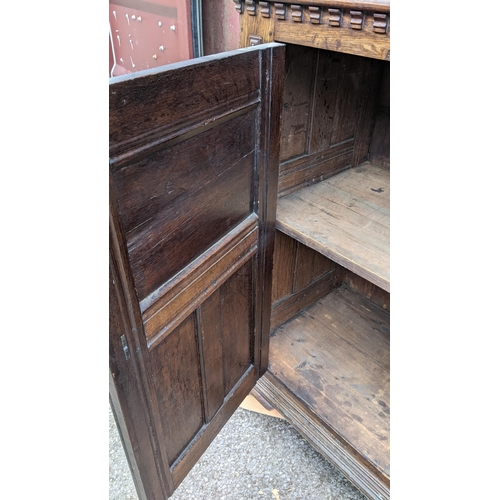 430 - An early 20th century Jacobean style oak court cupboard having a moulded cornice, panelled doors, wr... 