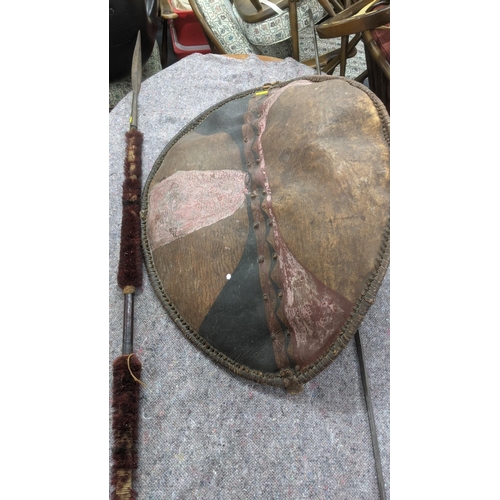 349 - A vintage Masai painted leather shield with a wooden handle, and two African spears, one part wooden... 