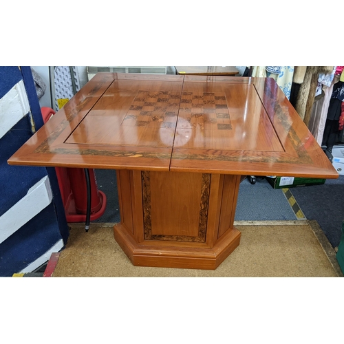 381 - An Indonesian hardwood foldover games table having a swivel top on a pedestal base with a single cup... 