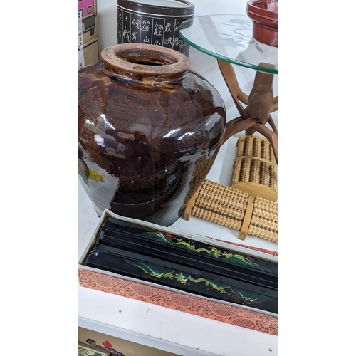 542 - A folding glass topped table together with an oriental stick stand, an earthenware glazed jar and ot... 