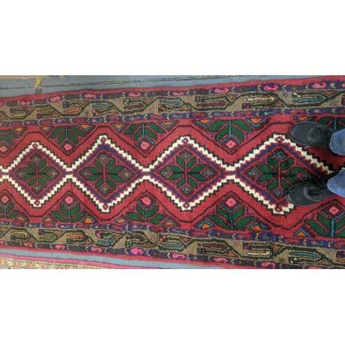 553 - Two handwoven rugs to include a Turkish red ground runner having floral motifs, 300cm x 86cm, the ot... 