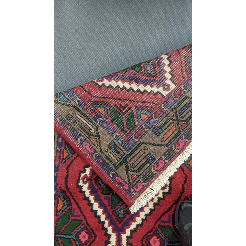 553 - Two handwoven rugs to include a Turkish red ground runner having floral motifs, 300cm x 86cm, the ot... 