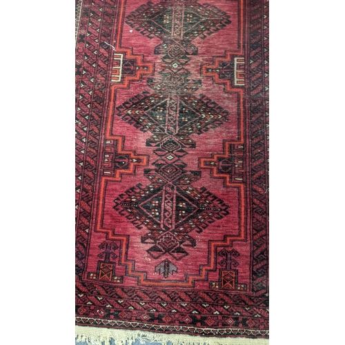 555 - Two handwoven rugs to include an Afghan rug on a red ground with repeating motifs, 205 x 95cm, the o... 