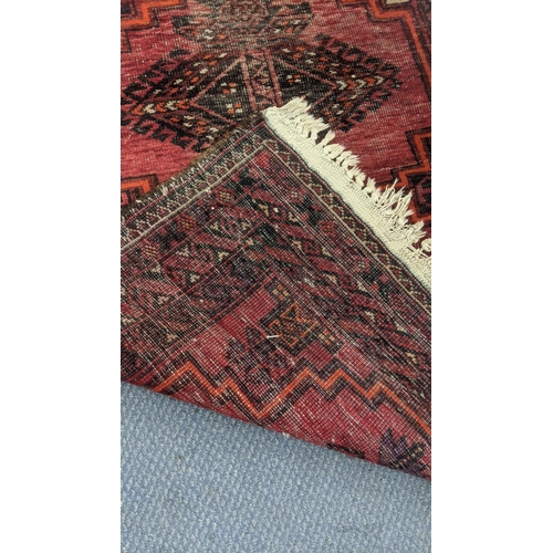 555 - Two handwoven rugs to include an Afghan rug on a red ground with repeating motifs, 205 x 95cm, the o... 