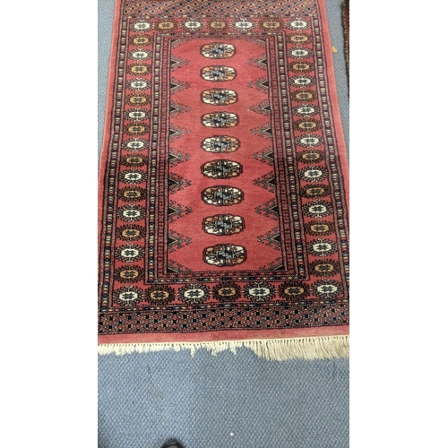 555 - Two handwoven rugs to include an Afghan rug on a red ground with repeating motifs, 205 x 95cm, the o... 